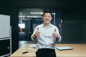 portret van geslaagd Aziatisch zakenman baas, Mens staand in kantoor in de buurt tafel op zoek Bij camera foto