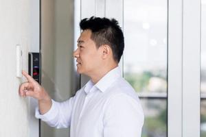 Aziatisch Mens toepassingen een deur klopper met een video camera naar Open de deur foto