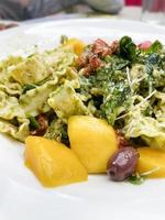 pesto pasta met mango en olijven Bij een restaurant foto