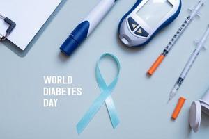 wereld diabetes dag tekst en blauw lint en glucosemeter, medisch benodigdheden Aan kleur achtergrond top visie foto