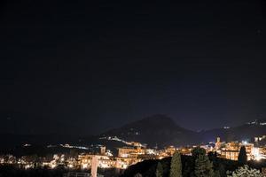 verlichte kust- stad en monteren Etna met donker lucht in achtergrond Bij nacht foto