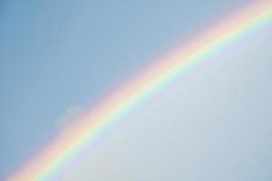 mooi visie van regenboog temidden van wolken aan het bedekken blauw lucht Aan zonnig dag foto