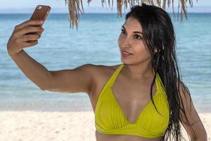 zwart haar- latina meisje portret nemen selfie Aan de zee achtergrond foto