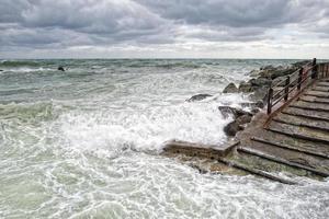zee in storm Aan rotsen met spatten foto