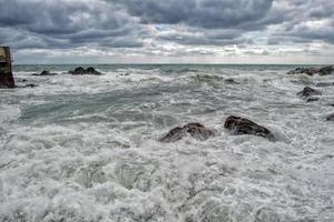 zee in storm Aan rotsen van Italiaans dorp foto