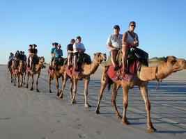 mensen genieten van een kameel rijden Aan kabel strand in de buurt brommer in western Australië foto