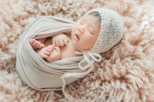 pasgeboren baby wrapprd in coconslaap op bont foto