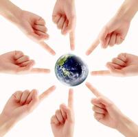 conceptuele symbool van een groen aarde wereldbol met multiraciaal menselijk handen foto