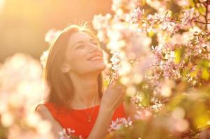 jonge vrouw in rode jurk wandelen in de tuin foto