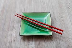 groen plein schotel met rood eetstokjes Aan grijs foto