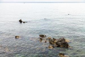 rotsen in water in de buurt waterkant in giardini naxos foto