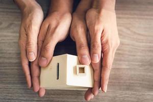 een stel heeft een klein houten huis om de aankoop van een nieuw huis te vertegenwoordigen foto