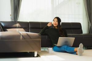 Aziatische vrouw die aan muziek op laptop luistert foto
