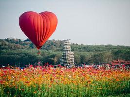 rode hartvormige luchtballon over veld van bloemen foto