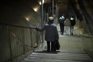 gepensioneerde gaat naar beneden trap in avond. oud vrouw wandelingen naar beneden stappen. foto