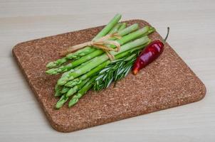 rauw asperges Aan houten bord en houten achtergrond foto