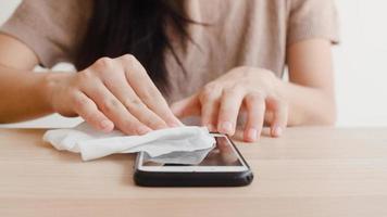 Aziatische vrouw met alcohol spray op mobiele telefoon. foto