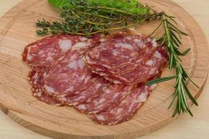 salami Aan houten bord en houten achtergrond foto