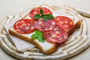 salami belegd broodje Aan houten bord en houten achtergrond foto