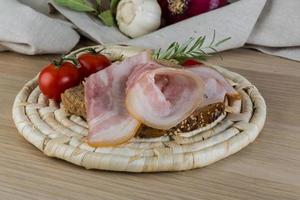 spek belegd broodje Aan hout Aan houten bord en houten achtergrond foto