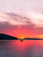 persoon op boot in water bij zonsondergang