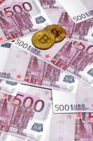 bitcoins over- stapel van vijf honderd euro bankbiljetten. traditioneel geld versus cryptogeld concept. goud munt bovenstaand 500 euro rekeningen. dichtbij omhoog foto