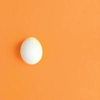 een wit Pasen ei Aan een helder oranje achtergrond foto