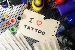 ik liefde tatoeëren. de tekst is geschreven Aan een klein vel van papier tussen divers uitrusting voor tatoeëren foto