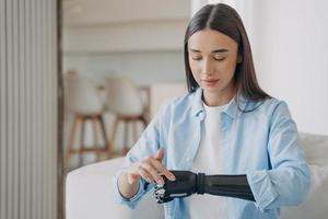 mooi jong gehandicapt meisje met bionisch prothetisch arm aan het leren naar beurt Aan hoog tech prothese foto