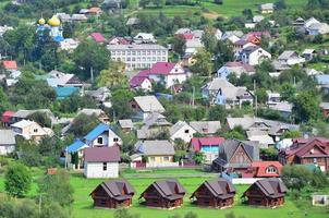 een mooi visie van de dorp van mezhgorye, Karpaten regio. een veel van woon- gebouwen omringd door hoog Woud bergen en lang rivier- foto