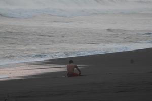 foto van een persoon spelen Aan de strand alleen, de water en zand van de strand kan worden gezien