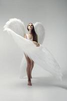 een romantisch engel meisje in een wit bodysuit met wit Vleugels foto