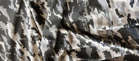 kleding stof met structuur van oekraïens leger korrelig camouflage. kleding met camo patroon in grijs, bruin en groen pixel vormen. officieel uniform van oekraïens soldaten foto