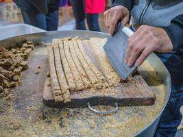 snijdend zoet pinda's stok met knap mes in souvenir winkel van fenghuang oud stad- foto