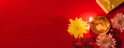 gelukkig divali. diya olie lamp, bloemen en geschenk dozen Aan rood achtergrond. vieren de Indisch traditioneel festival van licht. foto