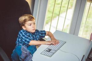 klein jongen spelen spellen Aan bureaublad pc Bij huis. foto