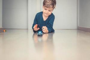 schattig kind spelen met auto speelgoed Aan de vloer. foto