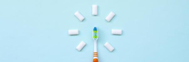 tandenborstel en kauwen tandvlees liggen Aan een pastel blauw achtergrond. top visie, vlak leggen. minimaal concept foto