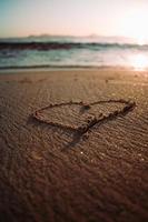 hart getrokken in zand op strand door water foto