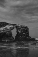 strand, water en rotswanden zwart-wit foto