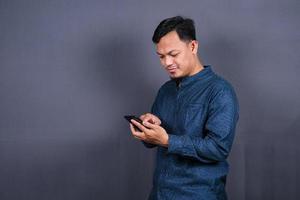 gelukkig Aziatisch Mens typen sms Aan grijs achtergrond. geïsoleerd, bedrijf concept foto