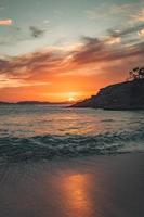 zand, water, bergen en kleurrijke zonsopganghemel foto