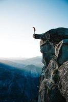 man die op klif met uitzicht op Yosemite foto