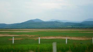 groen gras veld, met droog gebieden, een hek van berichten met met weerhaken draad limieten de land, foto