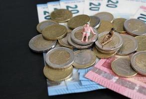 miniatuur beeldjes van een paar ontspannende en bruinen Aan een stapel van geld foto