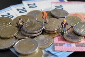 miniatuur beeldjes van arbeider werken Aan een stapel van geld foto