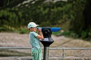 jongen kijken Bij panoramisch telescoop met uitzicht in vorderer gosausee, gosau, bovenste Oostenrijk. foto