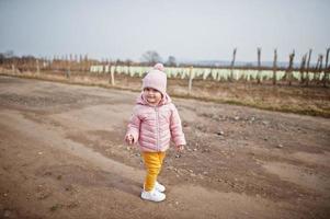 kleine baby draagt een roze jasje dat op het pad van de wijngaard loopt. foto