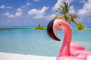 zomer zwemmen zwembad met opblaasbaar roze flamingo, luxe toevlucht hotel aan het zwembad. gelukkig blauw bewolkt lucht, tropisch paradijs eiland oneindigheid zwembad zee visie. vakantie, vakantie pret landschap. kom tot rust vrije tijd foto