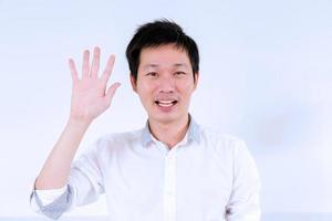 Aziatisch Mens golvend hand- voor communicatie Aan wit achtergrond foto
